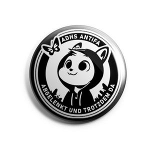 Könnte beinhalten: Schwarz-weißer Knopf mit einer Comicfigur, die ein Kapuzenpullover trägt. Der Text auf dem Knopf lautet "ADHS ANTIFA ABGELENKT UND TROTZDEM DA".