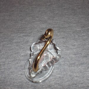 May include: A crystal swan figurine with a gold-plated neck and head. The swan is perched on a crystal base.