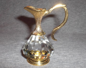 Puede incluir: Una jarra de cristal dorado con un cuerpo de vidrio transparente y un asa dorada. La jarra tiene un diseño facetado y una base redonda.