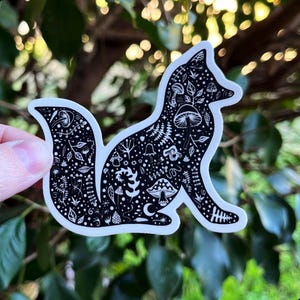 May include: Black and white sticker of a fox silhouette filled with detailed illustrations of mushrooms, leaves, and other forest elements.