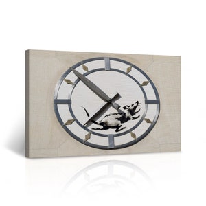 May include: A black and white rat stencil on a white clock face with silver hands and a silver rim. The clock face has gold diamond-shaped accents around the rim.