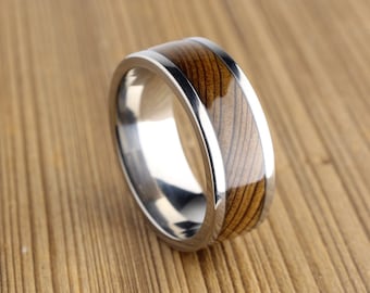 Op de afbeelding: Een zilveren ring met een bruine houten inlay. De ring is gepolijst en heeft een gladde afwerking.