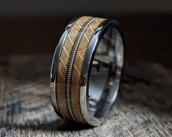 May include: A silver band with a wooden inlay and two silver wires running through the wood. The wood is a light brown color and the silver is polished.