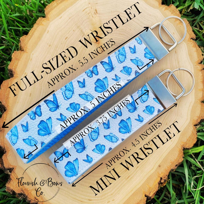 May include: Two wristlets with a butterfly pattern. The full-sized wristlet is approximately 5.5 inches long, and the mini wristlet is approximately 4.5 inches long. Both have a silver-colored metal ring. The wristlets are white with blue butterfly designs.