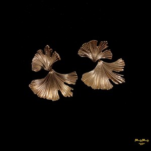May include: A pair of gold-toned earrings shaped like ginkgo leaves. The leaves are layered and have a textured finish.