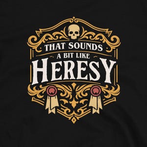 May include: Black t-shirt with a gold and white design featuring the text "THAT SOUNDS a bit like HERESY". The design includes a skull and decorative elements. The shirt is from Dungeon Arsenal.