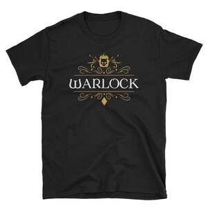 Może przedstawiać: Czarny T-shirt z złotym i białym wzorem przedstawiającym czaszkę z płomieniami i słowem "WARLOCK".