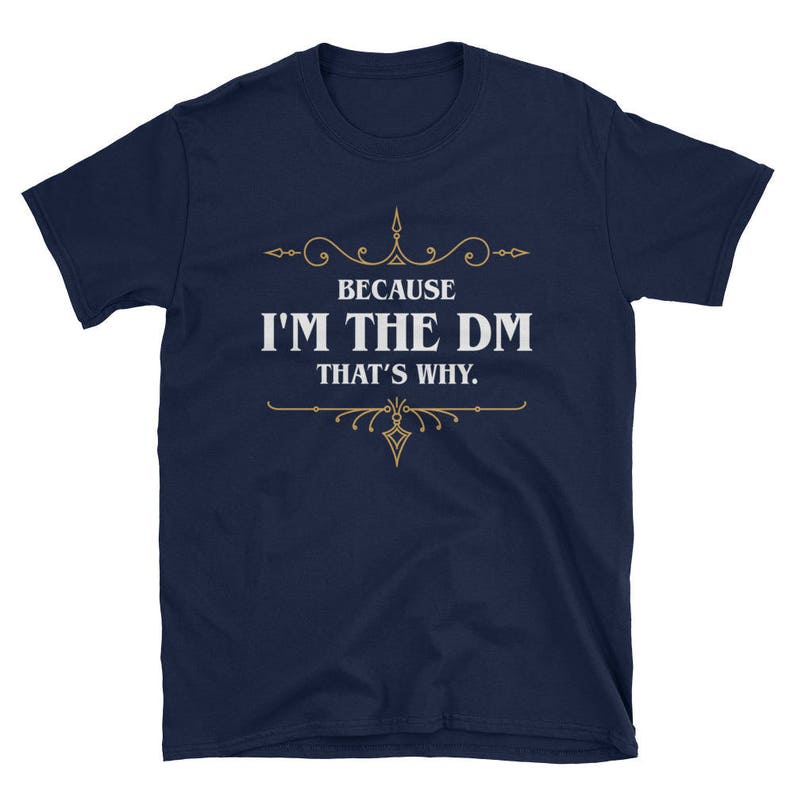 K&ouml;nnte beinhalten: Marineblaues T-Shirt mit dem wei&szlig;en Text "BECAUSE I'M THE DM THAT'S WHY." und goldenen Verzierungen. Das Shirt mit Rundhalsausschnitt und kurzen &Auml;rmeln ist f&uuml;r Rollenspiele geeignet.