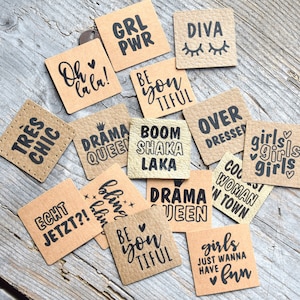 Puede incluir: Una colección de etiquetas de regalo de papel marrón con varias frases impresas en negro. Las frases incluyen "Tres Chic", "Oh lala!", "Grl Pwr", "Diva", "Be you TIFUL", "Drama Queen", "Boom Shaka Laka", "Over Dressed", "Girls Girls Girls", "Echt Jetzt?!", "Bling Bling", "Drama Queen", "Be you TIFUL", "Girls Just Wanna Have Fun", "Cool Woman In Town".