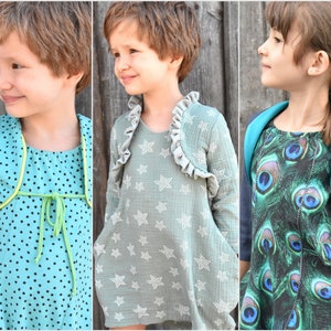 May include: Three young girls wearing different dresses with matching cardigans. The girl on the left is wearing a teal blue dress with white polka dots and a lime green cardigan. The girl in the middle is wearing a light green dress with white stars and a gray cardigan. The girl on the right is wearing a green and blue dress with a peacock feather pattern and a dark blue cardigan.