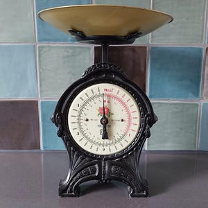May include: Black kitchen scale with a white face and a gold-coloured bowl. The scale has a floral design and the words "MADE IN FRANCE" and "E.T.E.Y." printed on the face.