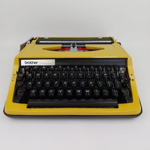 Máquina de escribir Brother Deluxe 800 QWERTY FUNCIONANDO con estuche rígido 1970 Años 70 amarillo en muy buen estado