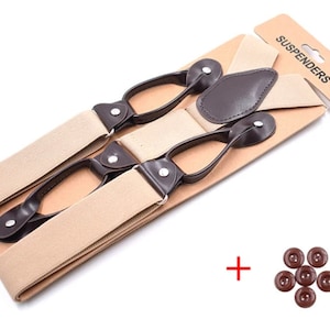 May include: Beige braces with brown leather accents and metal clips. The braces are packaged on a cardboard backing with the word "SUSPENDERS" printed on it. The package also includes a set of brown buttons.