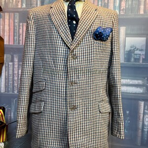 May include: A brown, blue and white houndstooth patterned blazer with a three-button closure. The blazer has a pocket on the left side with a blue patterned handkerchief.