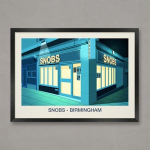 May include: A framed print depicting a teal-toned building with the word "SNOBS" in gold lettering. The building has large windows with a warm glow. The text "SNOBS - BIRMINGHAM" is printed at the bottom of the image.