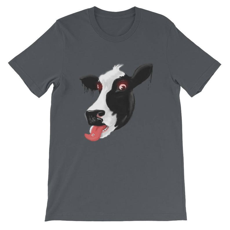 May include: A dark grey t-shirt featuring a graphic of a cow's face with red eyes and a pink tongue sticking out.