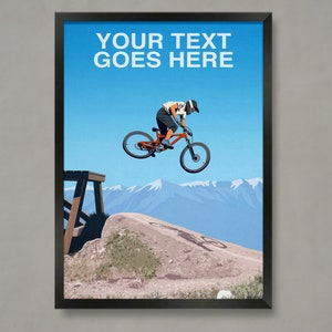 May include: A mountain biking poster featuring a cyclist in mid-air, performing a trick on a red mountain bike. The cyclist is wearing a helmet and a white shirt. The background features a blue sky, mountains, and a dirt path.