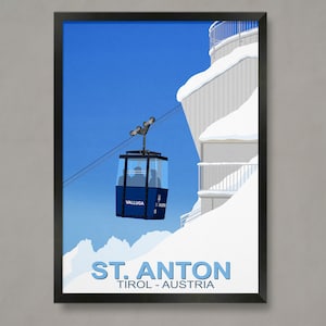 May include: A blue and white illustration of a gondola cable car with the text "Valluga" on the side. The gondola is traveling up a snowy mountain with a building in the background. The text "ST. ANTON TIROL - AUSTRIA" is at the bottom of the image.