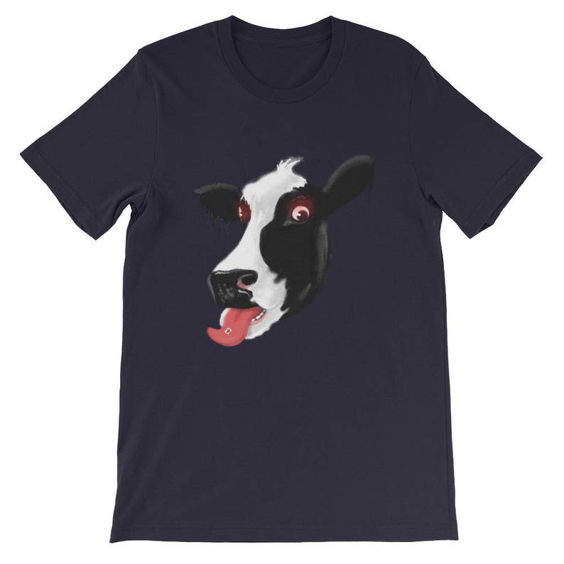 May include: A navy blue t-shirt featuring a graphic of a cow's face with its tongue sticking out. The cow has black and white markings and red eyes.