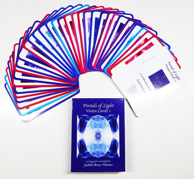May include: A deck of 33 meditation cards called "Portals of Light Vision Cards 1" by Judith Anne Thomas. The cards are arranged in a fan shape with blue, red and white borders. The box for the cards is blue with a white image of a portal of light.