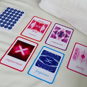 May include: Five cards with different coloured borders and abstract images. The cards have the words "oneness", "compassion", "empowerment", "forgiveness", and "clarity" printed on them.