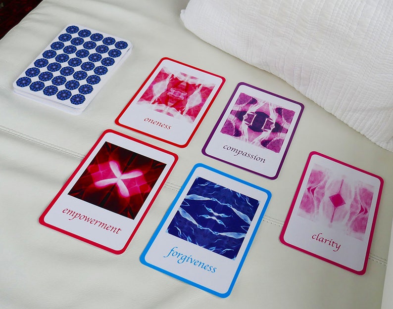 May include: Five cards with different coloured borders and abstract images. The cards have the words "oneness", "compassion", "empowerment", "forgiveness", and "clarity" printed on them.