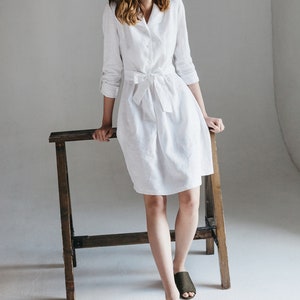 a woman in a white shirt dress sitting on a chair