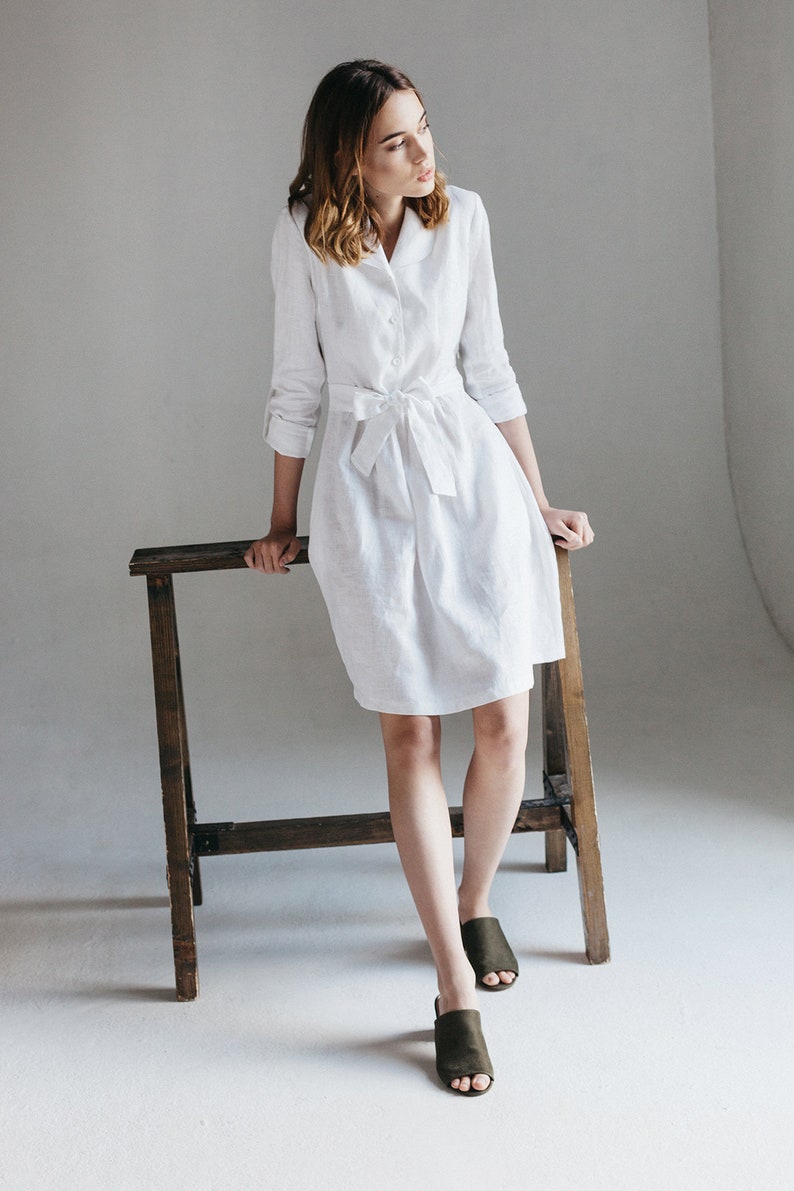 a woman in a white shirt dress sitting on a chair