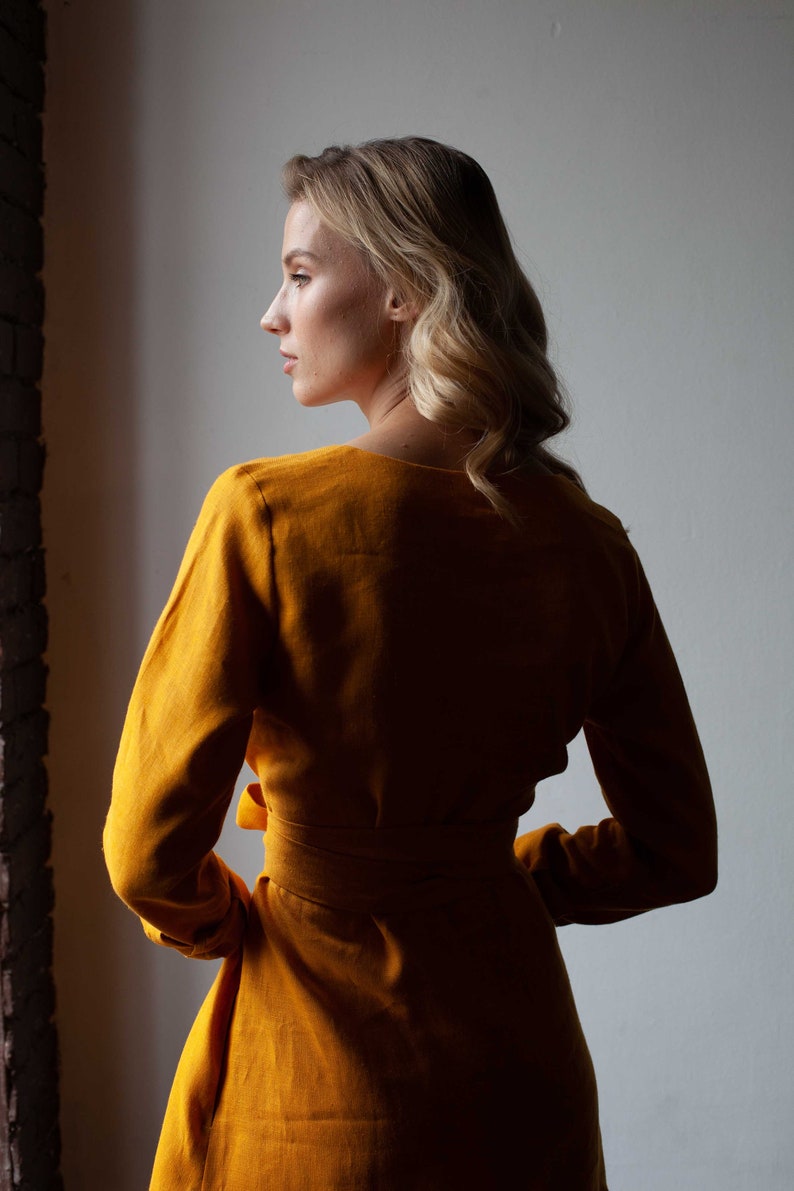 a woman in a yellow dress looking out a window