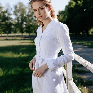 a woman in a white dress leaning against a fence