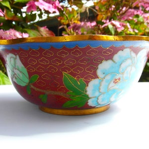 May include: A red and blue cloisonn&eacute; bowl with a floral design. The bowl has a scalloped rim and a gold trim.