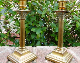 May include: A pair of antique brass candle holders with fluted columns and square bases. The candle holders are in excellent condition and have a beautiful patina.