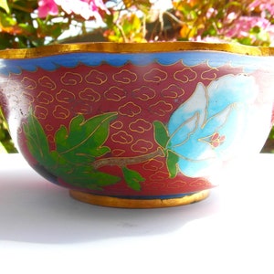 May include: A red and blue cloisonn&eacute; bowl with a floral design. The bowl has a scalloped rim and a gold trim.