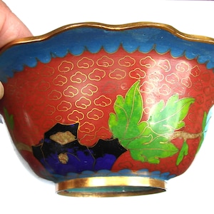 May include: A small, red, blue, green and gold cloisonn&eacute; bowl with a scalloped rim and floral designs.