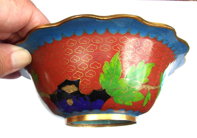 May include: A small, red, blue, green and gold cloisonn&eacute; bowl with a scalloped rim and floral designs.