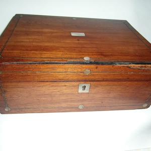 May include: A wooden box with a brass keyhole and metal accents. The box has a dark brown finish and is made of wood.