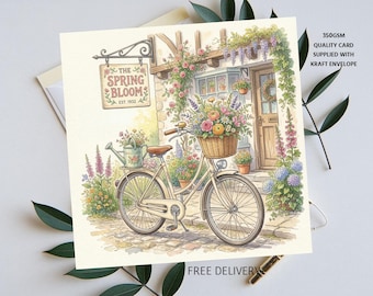 Puede incluir: Ilustración en acuarela de una bicicleta con una cesta llena de flores frente a una floristería. El letrero de la tienda dice "The Spring Bloom Est. 1932". La tarjeta es de color crema e incluye el texto "350GSM QUALITY CARD SUPPLIED WITH KRAFT ENVELOPE".
