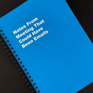 May include: A blue spiral bound notebook with the text "Notes From Meeting That Could Have Been Emails" printed in white.