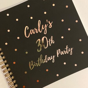 May include: A black notebook with a gold spiral binding, featuring gold foil polka dots. The cover displays the text "Carly's 30th Birthday Party" in elegant gold script.