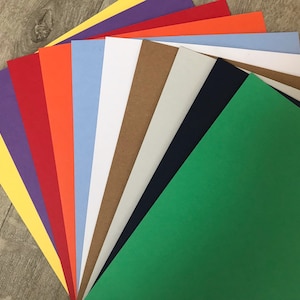 May include: A collection of 10 different coloured cardstock paper sheets, including yellow, purple, red, orange, light blue, white, brown, grey, navy blue, and green.