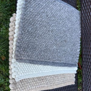 Peut inclure: Trois tapis tissés dans différentes nuances de gris et de beige. Les tapis sont faits d'un matériau texturé et ont une surface légèrement bosselée.