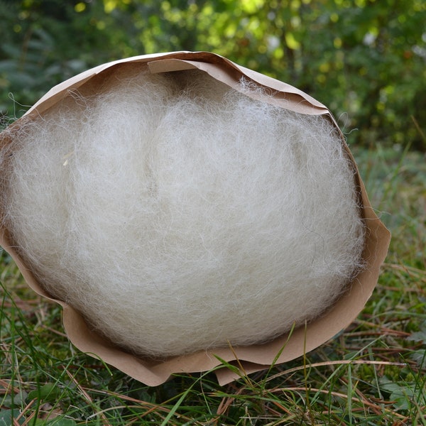 May include: A ball of white wool fiber wrapped in brown paper. The wool is soft and fluffy, and the paper is crinkled.