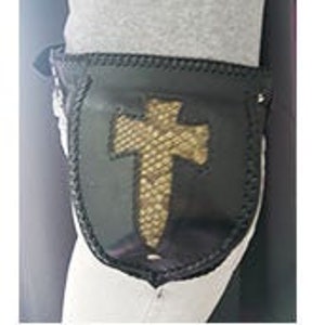 Może przedstawiać: Czarna skórzana nerka z wzorem krzyża ze skóry węża. Nerka ma zamek błyskawiczny i pętlę na pasek.