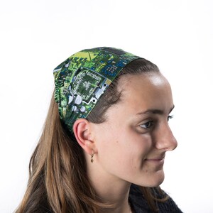 May include: A woman wearing a green and blue headband with a circuit board pattern. The headband is tied in a knot at the back of her head.