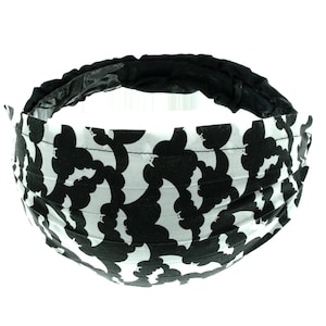May include: Black and white headband with a bat pattern. The headband is made of fabric and has a black elastic band.