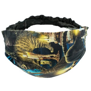 Puede incluir: Una diadema negra con una banda elástica extensible. La diadema está decorada con un estampado colorido de gatos y velas.