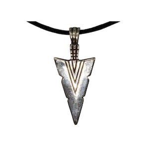 May include: A silver arrowhead pendant with a V-shaped design, hanging from a black cord. The pendant has a textured surface and a detailed top section. The necklace is shown against a white background.