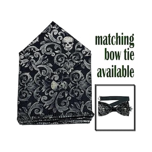 May include: Black and silver patterned pocket square with skull accents. The pocket square has a matching bow tie available. The design features a repeating pattern of swirls and skulls.
