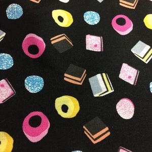 May include: Black fabric with a repeating pattern of colourful sweets. The sweets are in the shapes of squares, circles, and ovals. The fabric is ideal for crafting projects.