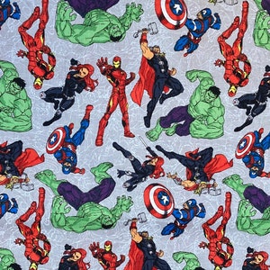 Può includere: Un tessuto grigio chiaro con un motivo ripetuto di supereroi Marvel. Il design include Iron Man in rosso e oro, Capitan America con il suo scudo, Thor con il suo martello, Hulk e Vedova Nera.